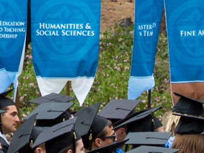 Academic department banners show behind graduates in their mortarboards at the 2019 Sierra Nevada University Commencement