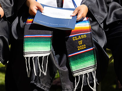 Sierra Nevada University 2022 graduating senior with their class stole and program.