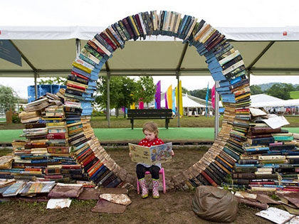 Child encircled with books at book fair in Hay-on-Wye, Wales famous as the Town of Books