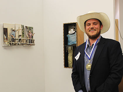 Student symposium winner Ryan McCarthy stands next to his exhibit I am You. You are Me.