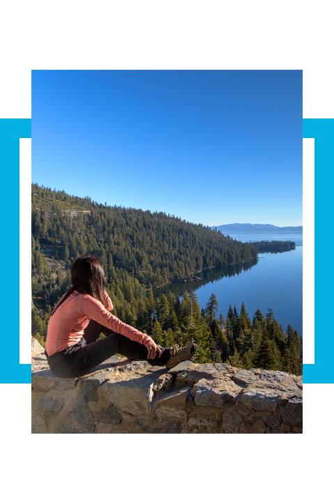 Sierra Nevada College of Entrepreneurial Leadership Student sits on a wall overlooking Emerald Bay
