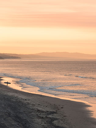 Surfer on the beach at San Elijo, sunrise. Photo by Digital Arts and Outdoor Adventure Leadership major Garrett Ramos