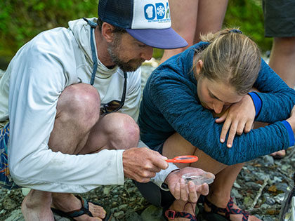 professor Darryl Teittinen helps a student identify a benthic macroinvertebrate - Sierra Nevada University environmental science and outdoor adventure leadership students in field courses on the Wild and Scenic Rogue River