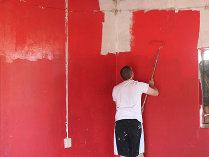 Student in Sierra Nevada University's South Africa Service Learning Africa course renovating a rural preschool - painting the walls red!