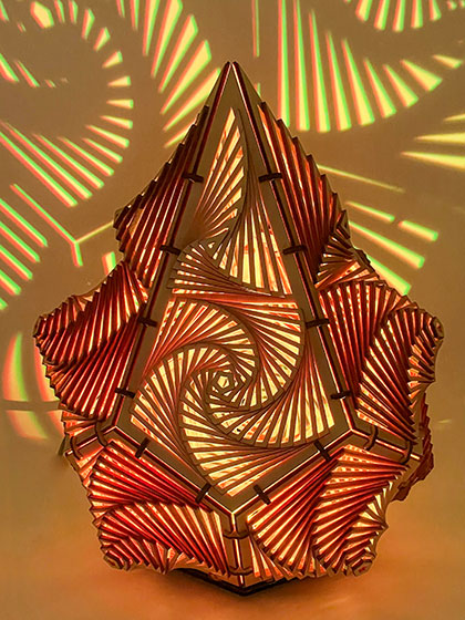 intricate lamp, illuminated amber, by laser-cut artist Eric Burns