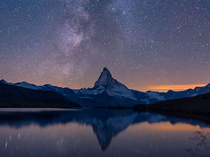 mountain silhouetted against an evening sky sprinkled with stars