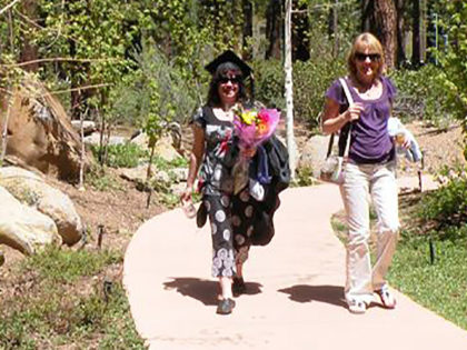 A graduating student and her proud mother walking through the Sierra Nevada University campus on a sunny Commencement Saturday