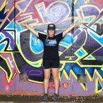Madeleine Hall, Marketing major, poses in front of brightly painted wall