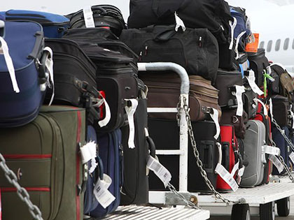 luggage piled on carts at the airport waiting to be loaded